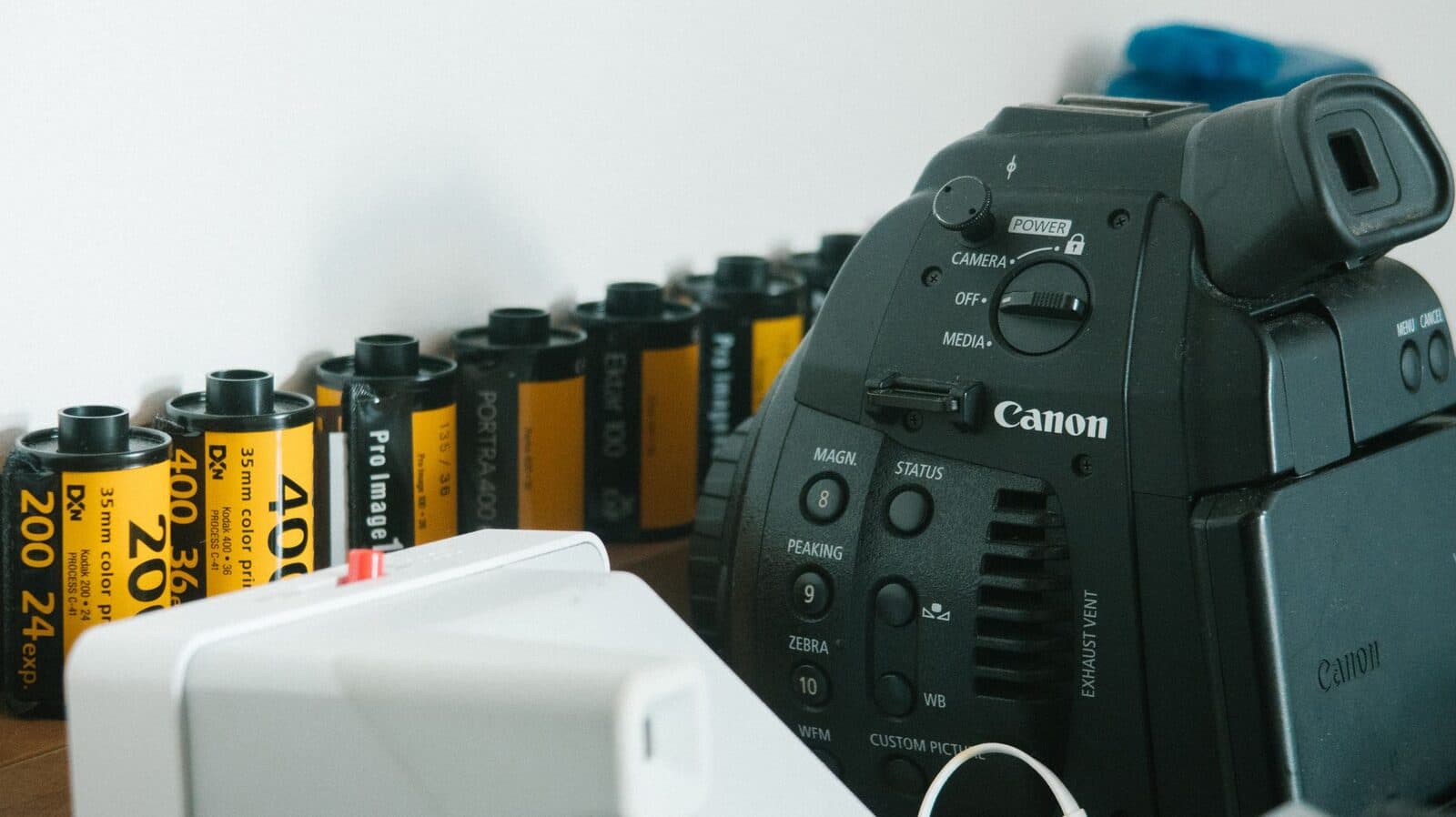 A close-up image of camera equipment alongside several rolls of 35mm film.