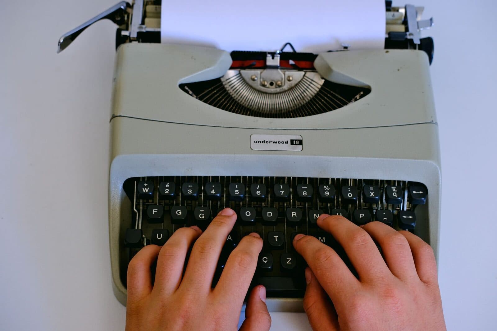 Close-up of hands typing on a classic Underwood typewriter with paper.