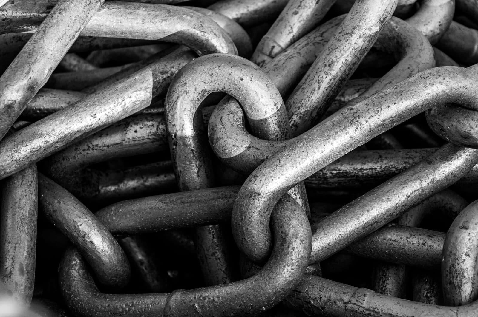 Black and white close-up of industrial steel chains showcasing their texture and strength.